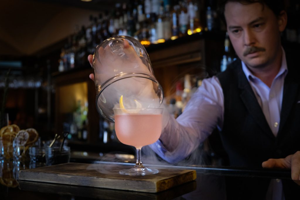 A photo of a bartender serving a smoky drink